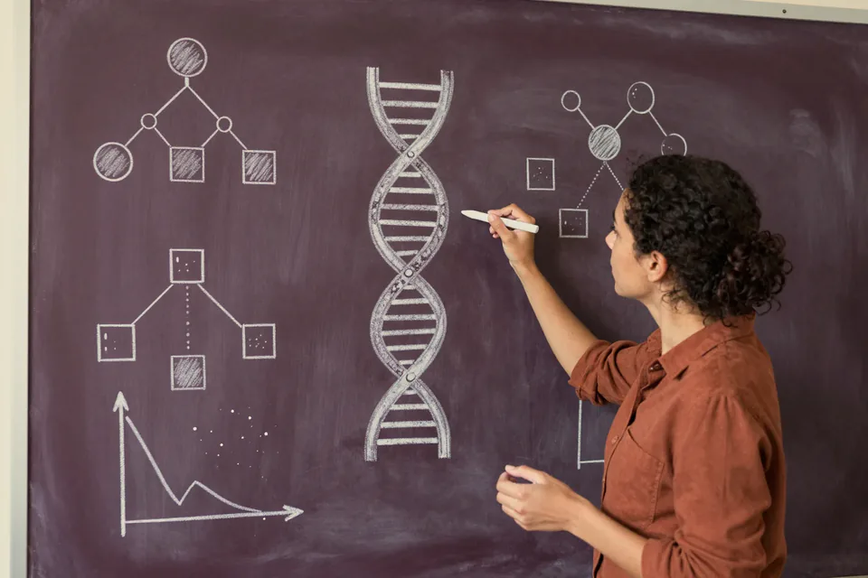 A scientist drawing a DNA double helix and diagrams on a chalkboard.