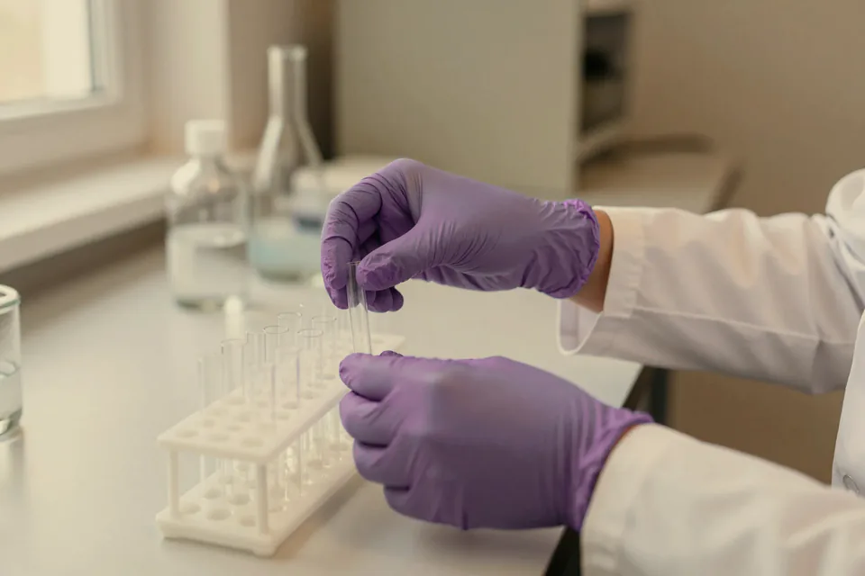Gloved hands placing a tube into a rack.